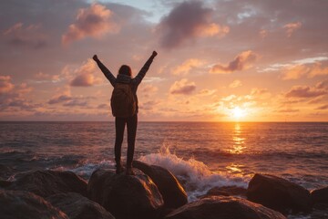 Fototapeta premium Person by ocean with raised arms at sunset