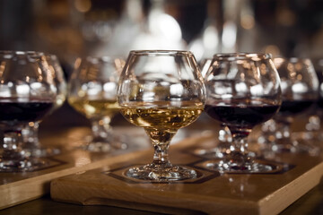A wine tasting flight with glasses of red and white wine arranged on wooden paddles in a warm,...
