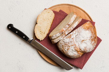Freshly baked bread cut with knife on a wooden board. top view Sliced bread and knife