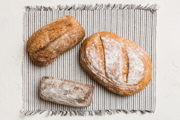 Assortment of freshly baked bread with napkin on rustic table top view. Healthy unleavened bread. French bread