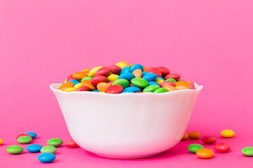 Multicolored candies in a bowl on a colored background. birthday and holiday concept. Top view with copy space
