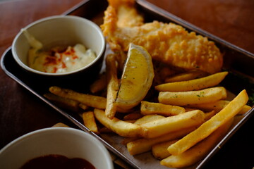 Fish and Chips with Fries, Lemon Wedge, and Dipping Sauce on a Metal Tray