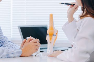 Orthopedic surgeon shows knee model to patient in human knee hospital. Knee joint diseases and...