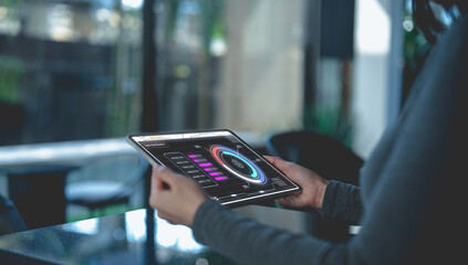 A person interacts with a digital dashboard on a tablet in a modern indoor environment.