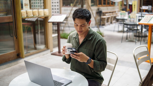 Casual businessman checking his smartphone during a coffee break at an outdoor cafe.