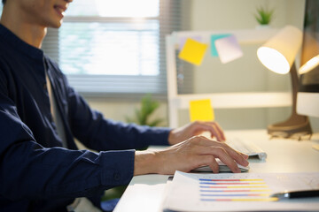 Close up of businessman working on computer with financial charts at desk.