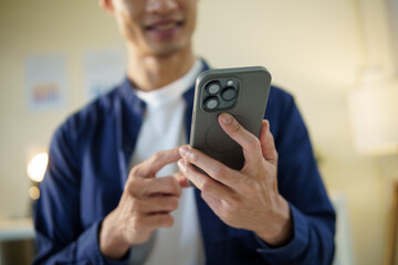 Businessman using a smartphone, focused on the screen with a relaxed and positive expression.