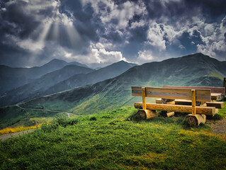 Wooden bench with vistas on mountains near Saalbach Hinterglemm Leogang ski resort during summer day