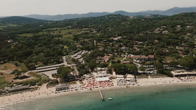 drone view of saint tropez beach. people relaxing under red sun loungers