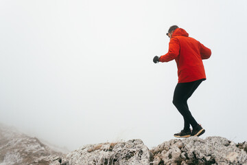 Man Climbing Rocky Hill in Fog