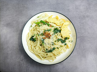 Mie Pangsit or Mie Ayam Pangsit. Noodles in a plate that are popular in Indonesia with minced chicken topping, green mustard greens. isolated on gray background