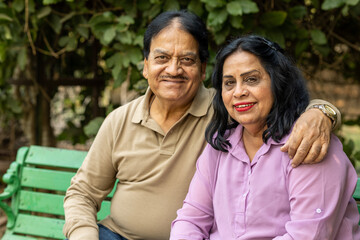 Naklejka premium Indian happy senior couple embracing at park. Asian Happy loving Senior Couple having fun in vacation time. Senior citizens care hugging or date at the park for romance after retirement