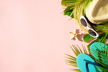 Summer cloth and accessories with palm leaves on pink background. Flat lay with space for design.