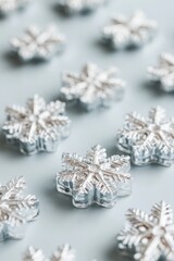 Fototapeta premium Macro close-up of silver snowflake decorations arranged on a light blue surface creating a festive winter holiday scene