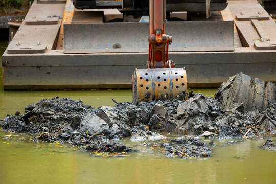 Excavator dredging riverbed in Thailand, environmental cleanup