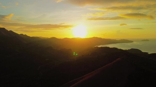 Golden sunrise over Mount Tapyas and Coron Bay with silhouetted mountain ridges calm sea and warm clouds across Palawan Philippines