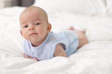 Cute little baby on bed at home, space for text
