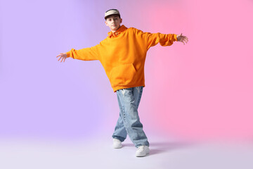 Boy in stylish clothes dancing on color background