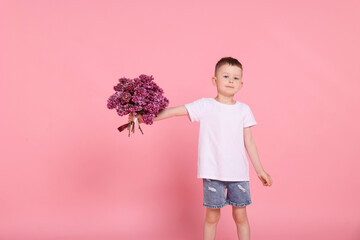 Little boy with bouquet of lilac flowers on pink background