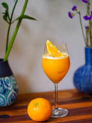 Orange juice. A glass of fresh orange juice mocktail with ice on wooden table. Refreshment for summer.