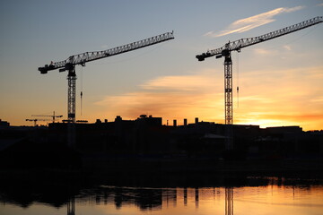 Sunset cityscape featuring silhouettes of construction cranes against a glowing sky, Porvoo, Finland