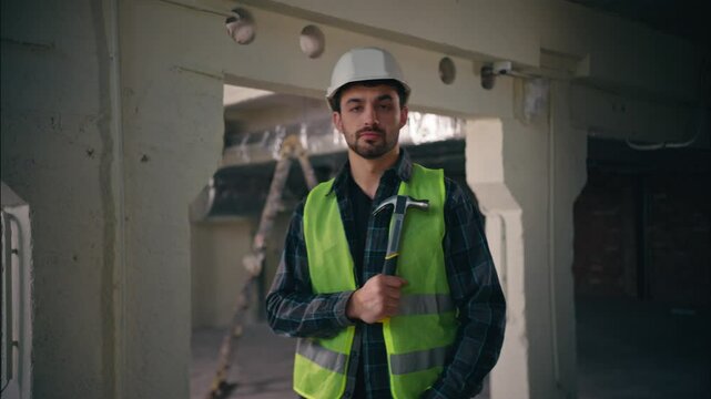 Serious Caucasian builder guy holding hammer in construction technician electrician repairman throw tool equipment male engineer preparing for work handyman building man contractor constructing repair