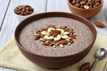 Fototapeta premium A bowl of warm oatmeal topped with various nuts, perfect for breakfast or snack