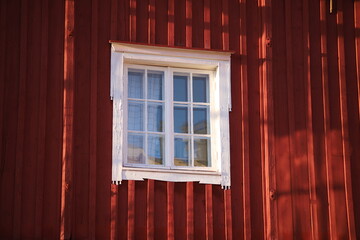 Close-up of the facade of a red-painted wooden building in classic Scandinavian style, featuring a window with crisp white frames, Porvoo, Finland