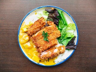 Japanese curry rice with crispy fried chicken pieces and vegetable on wooden table. Great for menu design, food blog, restaurant promotion and more