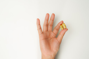 Male hand holding soft gels, Fish oil capsules, omega 3, omega 9, vitamin D, vitamin E, supplements