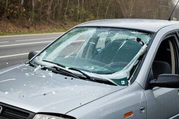 Obraz premium Car with cracked windshield sitting on roadside, perfect for accidents or breakdowns scene