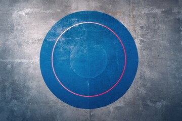 Aerial view of blue wrestling mat with red ring on gray concrete floor for sports competition training and exercise