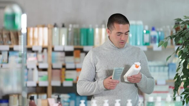 Male buyer chooses skin cream at the drugstore. High quality 4k footage