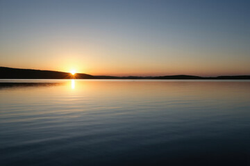 Obraz premium Serene moment of sunset over a peaceful lake
