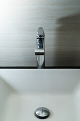 Shiny faucet with water flowing in a clean bathroom sink