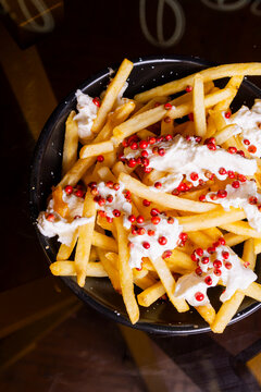 Porzione di patate fritte guarnite con burrata fresca e caviale di pomodoro e servite come antipasto in una braceria