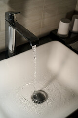 Shiny faucet with water flowing in a clean bathroom sink