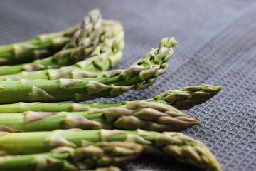 Green asparagus on black textile background. Asparagus close up. Bunch of fresh green asparagus on black fabric. Veggies background. Vegetables on kitchen towel