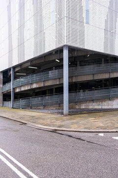Minimalist urban corner with geometric metal facade and empty road, perfect for backgrounds or architectural concepts with clean lines and negative space.