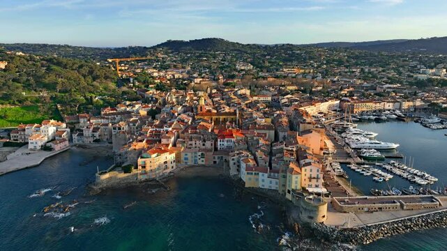 Aerial view of Saint-Tropez's colourful houses, church tower on the French Riviera. View from above of public beach and Catholic church, Cote d'Azur, a popular destination for travel in Europe