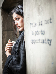 A Photo Opportunity. A beautiful young mixed race girl posing ironically by a graffiti slogan. From a series of images with the same model.