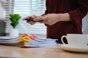 Close-up of businesswoman in office sorting through large amount of financial documents and files, filled with documents, accounts and reports.