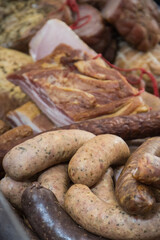 Fresh prepared smoked hams and sausages with spices on market stall
