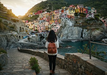 A woman with a backpack admiring the colorful village of Manarola in Cinque Terre, Italy.