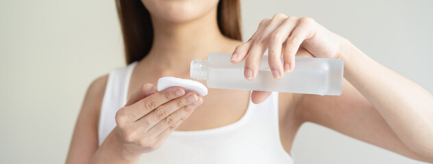 Close-up view hands of woman using toner and cotton pad to remove makeup