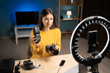 Female photographer content creator using smartphone for social media, vlogging and livestreaming. Influencer photographer hosting educational podcast showing camera and flash, giving tips