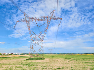 High voltage power lines crossing a field under blue sky