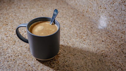 Gray mug with coffee on a granite countertop 