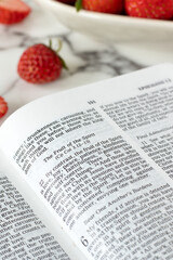 Fruit of the spirit text in open holy bible book with strawberries on table. Biblical concept of...