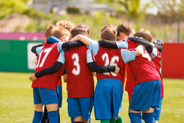Young Soccer Team in Red Jerseys Huddles Together Before a Match on a Sunny Day, Showing Team Spirit and Unity